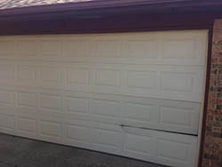 Displaying a home steel garage door in need of repairs in Dallas Texas and being serviced by Action Garage Door Technician 4